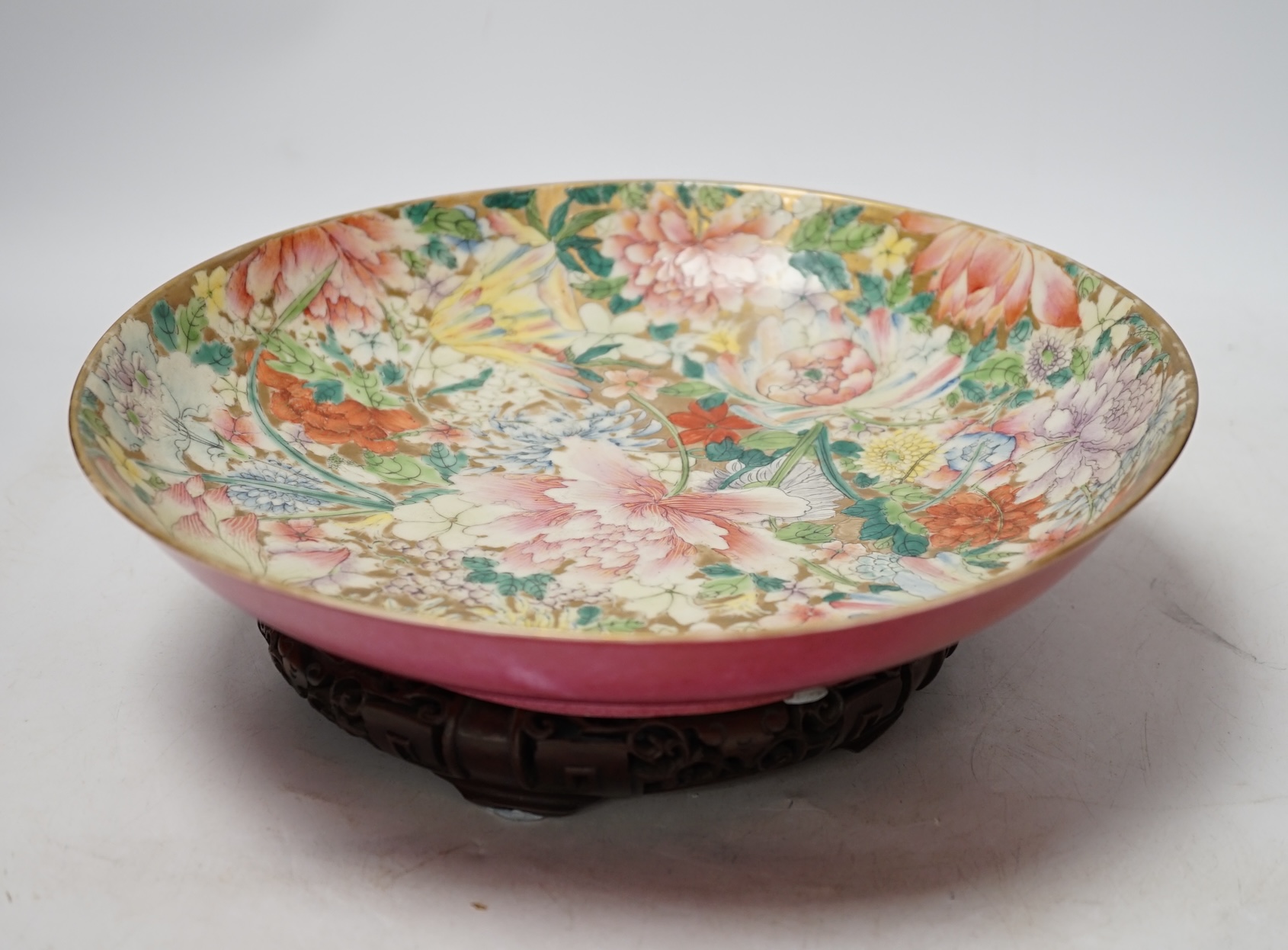 A Chinese enamelled porcelain millefleur dish, Guangxu mark and probably of the period, on wooden stand, diameter 28cm. Condition - restored